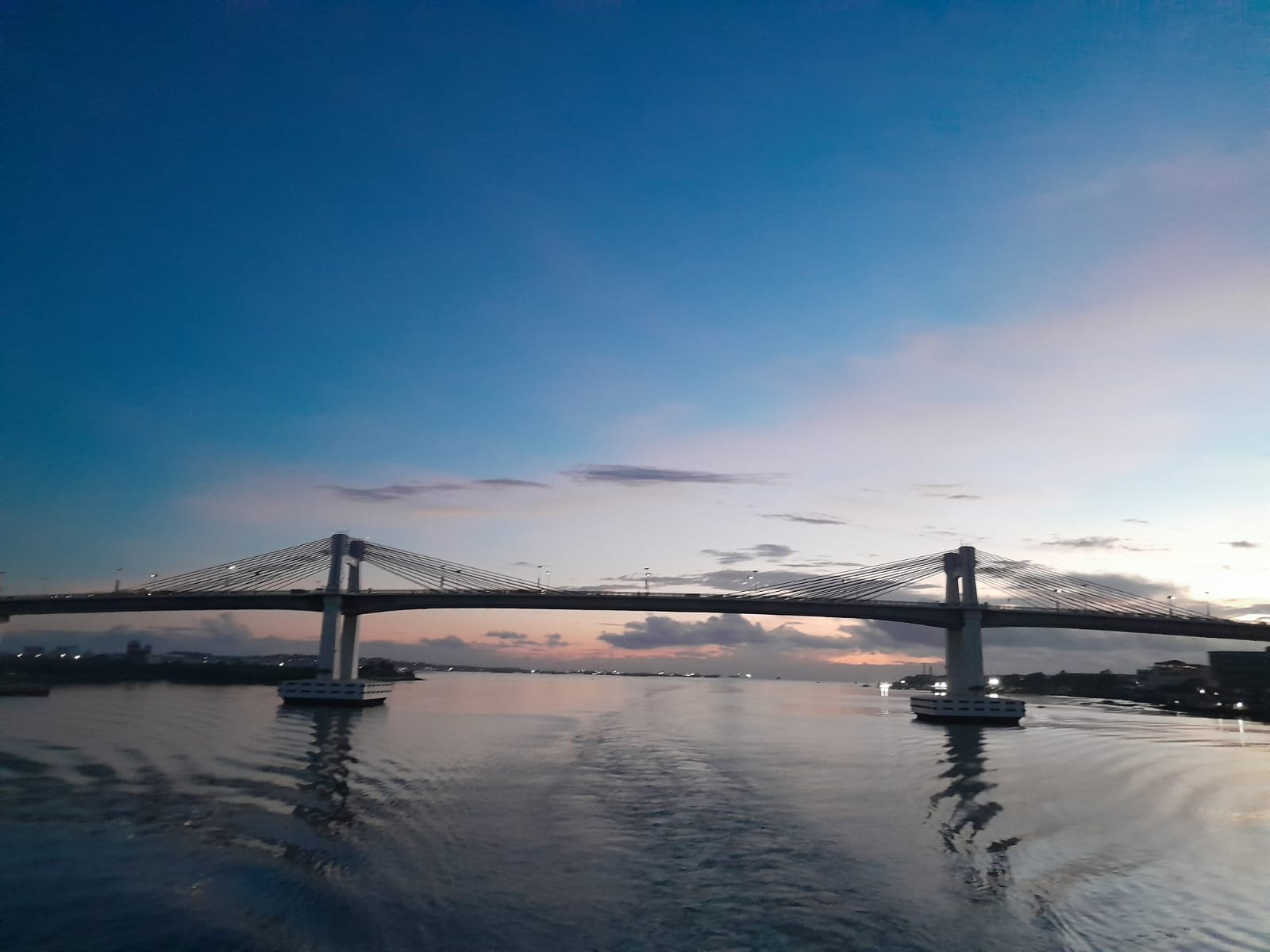The Marcelo Fernan Bridge with the sun rise acting as a backdrop reflecting colors of yellow, whitish pink, whilst blending with the fading night blue sky.